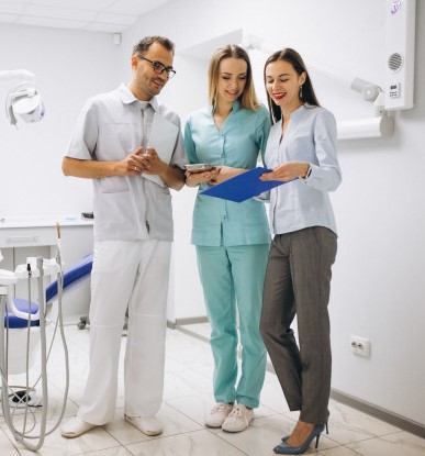 Three people standing in a room with one holding a tablet.