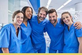 A group of doctors standing together in blue scrubs.