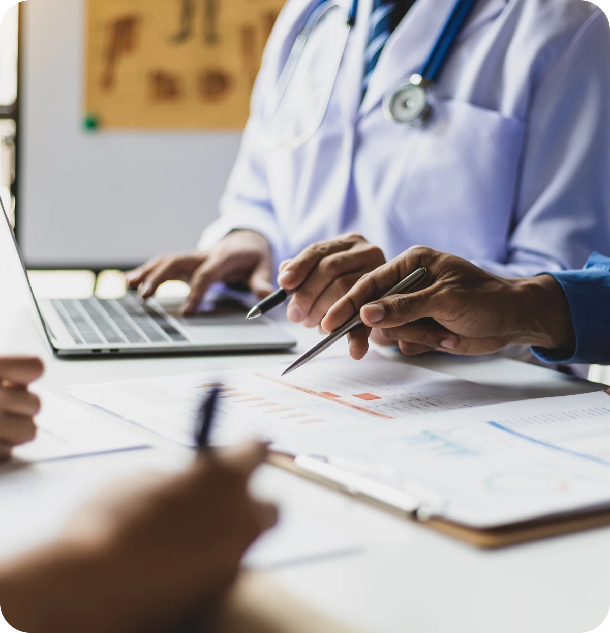 Doctors reviewing medical documents and using laptop